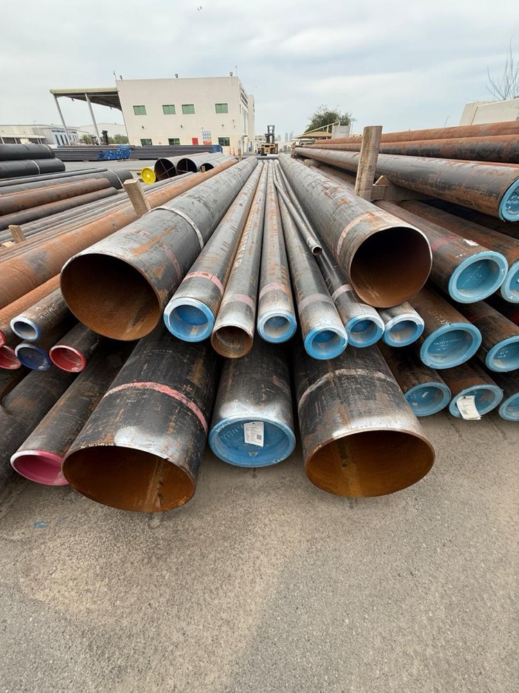 Coiled steel line pipe stacked in an oilfield equipment yard